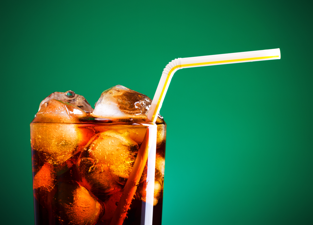Glass of diet soda with ice and a green background 