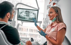 Dentist showing x-ray image to patient sitting in dental chair