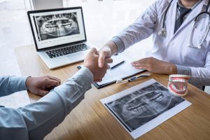 Dentists shaking hands with dental x-ray images in the background