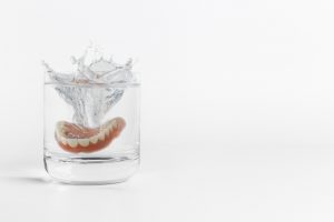 Dentures splashing into a glass of water