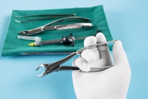 white glove holding dentistry tools for extracting teeth