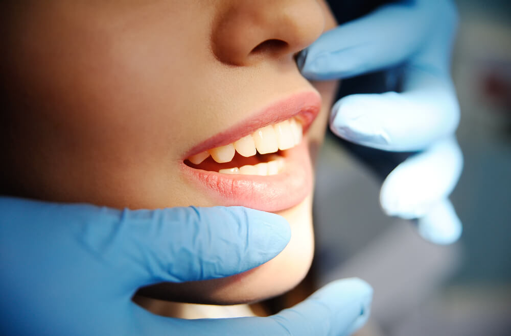 dentists gloves examining woman's front teeth