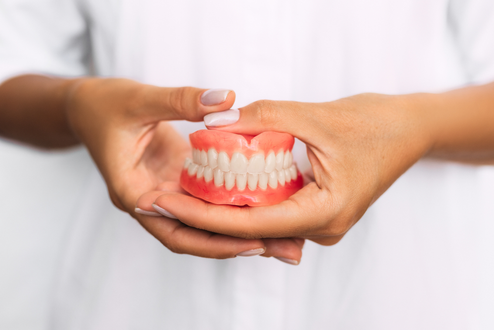 Person holds their whitened dentures