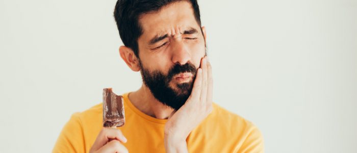 Man with tooth sensitivity to cold eats ice cream, in pain