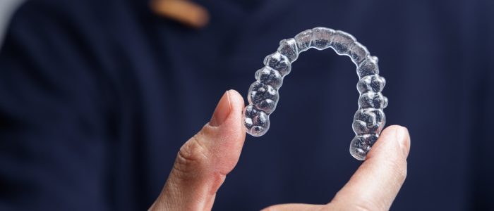 A person holds up their Invisalign aligner trays.